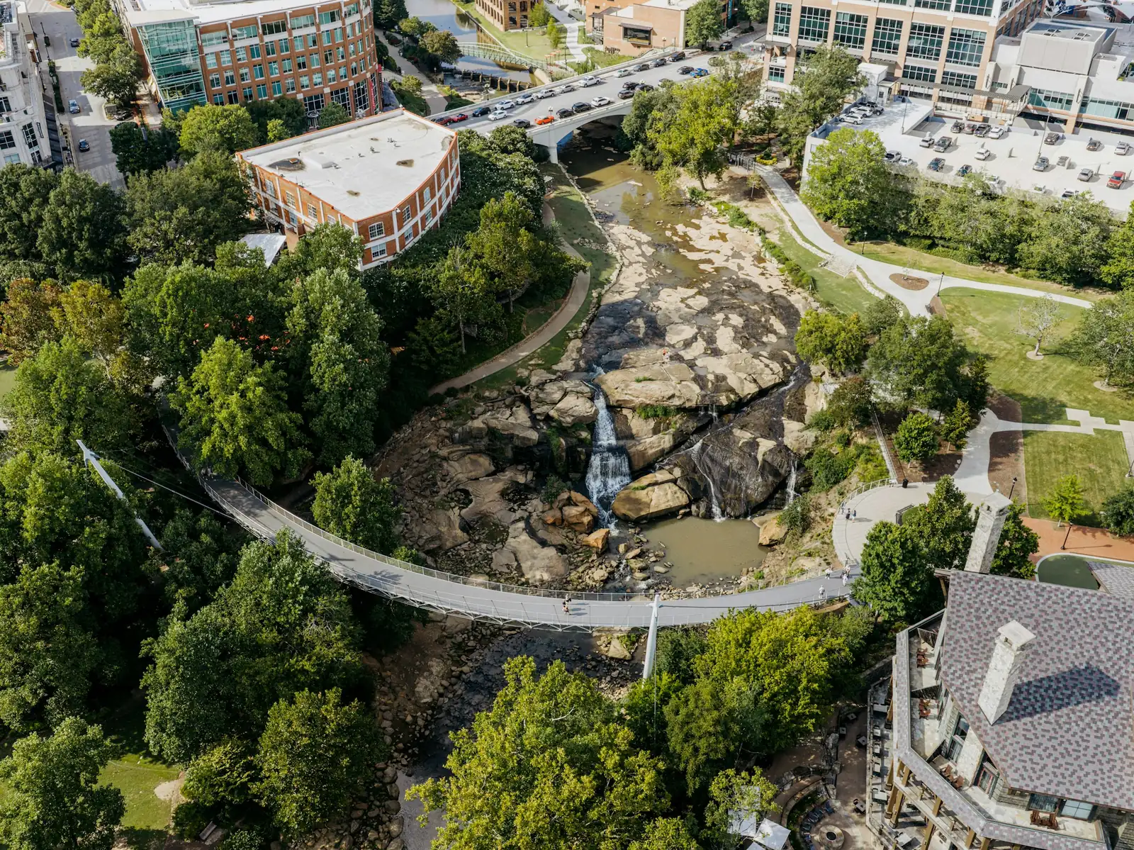 Aerial view of the Liberty Bridge curving over the Reedy River falls in Falls Park, downtown Greenville, South Carolina